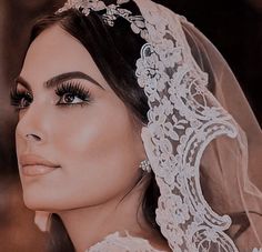 a woman wearing a veil with flowers on her head and eyeliners is looking off to the side