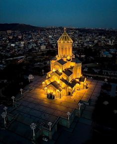 an aerial view of a church lit up at night with the city in the background