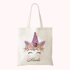 a white tote bag with an unicorn's face and flowers on the front