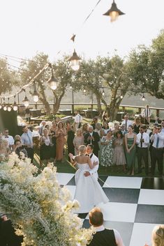 a bride and groom are dancing on a checkered floor in front of an audience