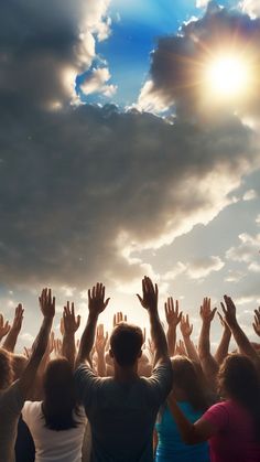 a group of people standing in front of a cloudy sky with their hands raised up