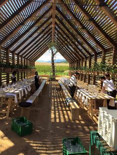 people are sitting at tables under a wooden structure with white tablecloths and place settings