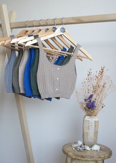 a rack with clothes hanging on it next to a vase