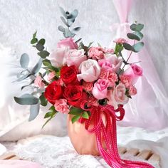 a vase filled with lots of pink and red flowers