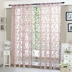 a living room with pink curtains and pictures on the wall