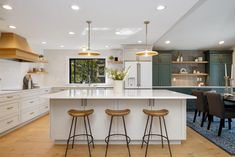 a large kitchen with two bar stools next to an island in the middle of it