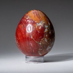 a red marble egg sitting on top of a metal stand