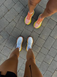 two people standing next to each other on a brick walkway with their feet up in the air