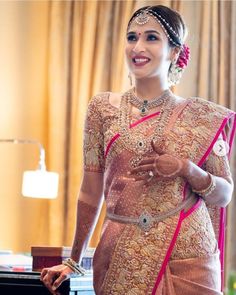 a woman standing in front of a desk wearing a pink and gold sari with matching jewelry