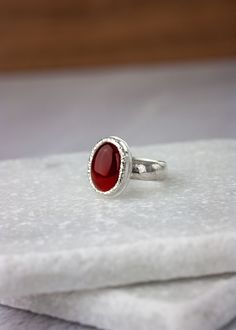 A vibrant red Carnelian is set in a thick bezel with a sparkling hammered texture. Made completely of sterling silver, this modern ring features clean lines and minimalist styling with just enough texturing to focus the mind. The name 'Orka' (Icelandic for 'energy') is given to this ring because, to some, Carnelian symbolizes vibrant energy, life, and creativity. US Size 9 Details:Focal Dimensions: 0.75 in x 0.5 (18 x 14mm)Band: 6 mm wide and slightly domed Modern Red Cabochon Ring, Red Carnelian Signet Ring For Anniversary, Red Carnelian, Carnelian Ring, Vibrant Energy, Modern Ring, Hair Ornaments, Vibrant Red, The Mind