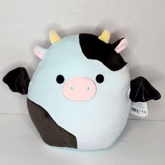 a stuffed cow with horns and black ears on it's head, sitting against a white wall