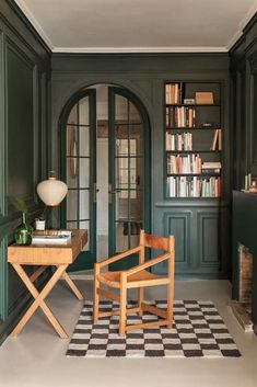 a chair and table in front of a green door with bookshelves on either side