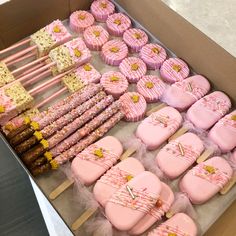 a box filled with lots of pink and yellow decorated cookies next to marshmallows