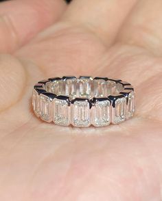 a close up of a person holding a ring in their hand with diamonds on it