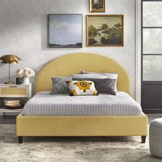 a yellow bed sitting in a bedroom next to a window with pictures on the wall