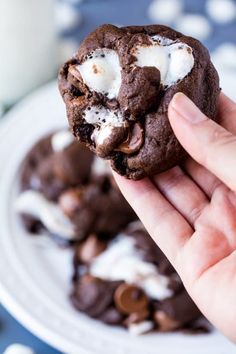 a hand holding a chocolate cookie with marshmallows