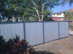 a large metal fence in front of a house with trees and bushes around the perimeter