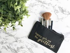 a makeup bag with brushes in it sitting on a marble counter top next to a potted plant