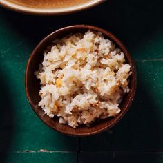 two bowls filled with rice on top of a green tablecloth next to a cup of coffee