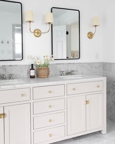 a bathroom with two sinks, mirrors and lights on the wall next to each other