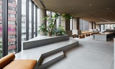 an office lobby with large windows and plants on the wall, along with couches