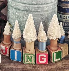 small christmas trees are sitting on blocks in front of an old pail and other items