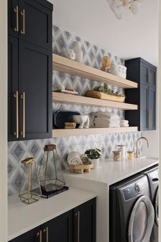 a washer and dryer in a room with blue cabinets, white counter tops and shelves