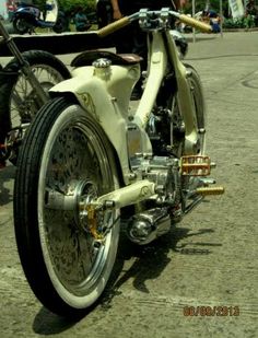 a white motorcycle parked on top of a street next to other people in the background