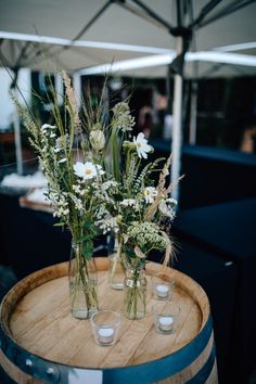 three vases filled with flowers sitting on top of a barrel