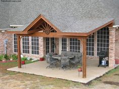 a covered patio with chairs and table in front of it