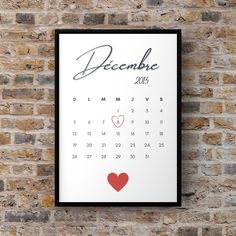 a calendar hanging on a brick wall next to a brick wall with a red heart