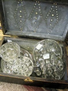 an open suitcase filled with lots of clear glass jars on top of a carpeted floor