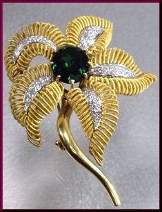 "The captivating flower brooch has a center oval shaped 10.00 ct deep forest green tourmaline. It dates from the 1960's. It is surrounded by 4 gold coiled leaves encrusted with 1.75 ct of round diamonds in the center of each leaf. It all gracefully blooms out of the golden stem. This is enticing appeal all swathed up into a pin. The pin weighs 45 grams. It measures 2 ½ \" long and 2\" wide at its widest point. P 518S SIX MONTH LAY-AWAY AVAILABLE - PLEASE CONTACT ME TO SET UP A PLAN" Luxury Green Brooch For Formal Occasions, Luxury Green Brooch For Anniversary, Luxury Green Brooches For Anniversary, Green Fine Jewelry Brooches For Wedding, Luxury Green Brooches For Wedding, Fine Jewelry Green Brooches For Anniversary, Green Fine Jewelry Brooch For Anniversary, Fine Jewelry Green Brooch For Anniversary, Elegant Green Flower Brooches