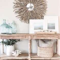 a wooden table topped with vases and pictures next to a wall mounted sunburst