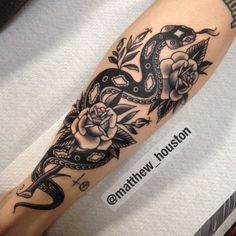 a snake and roses tattoo on the arm