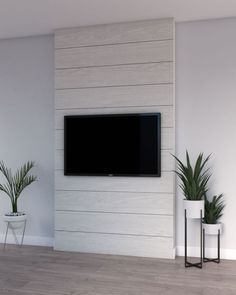 a flat screen tv mounted to the side of a wall next to potted plants