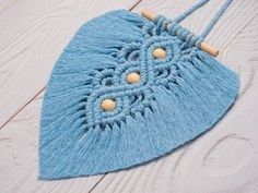 a crocheted blue bag with wooden handles on a white wood floor next to a pair of scissors