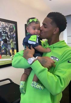 a man in a green hoodie holding a small child with his face close to the camera