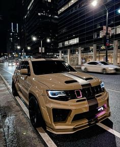 a brown jeep parked on the side of a road at night with other cars in the background