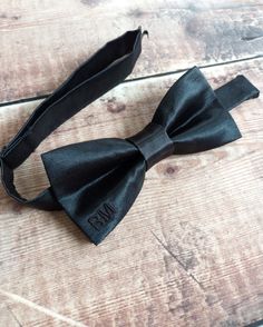 "This pre-tied men's bowtie comes in a simple and classic style. With it's slim batwing shape you can choose from a variety of colours. The matching embroidered initials add a subtle and personal twist, these are made in a matching thread colour featured on the front bottom right corner of the bow. DETAILS: This bowtie is approx. 5\" by 2.5\" and fastens with an adjustable strap fitting up to a max neck width of 18 inches with a hook and eye closure. We can make wider widths upon request. Max 3 Dapper Adjustable Bow Tie For Father's Day, Standard Tie Bow With Ribbon For Black-tie Events, Adjustable Dapper Bow Tie For Father's Day, Dapper Adjustable Bow For Black Tie Events, Adjustable Dapper Bow For Black Tie Events, Fitted Bow Tie As A Gift, Dapper Adjustable Tie With Satin Bow, Fitted Bow Tie As Gift, Adjustable Bow Tie Back Bow As Gift