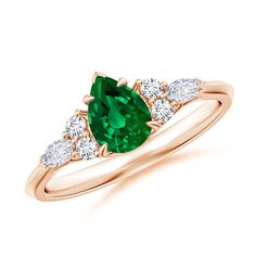 a ring with an oval cut green stone and three pear shaped diamonds on the side