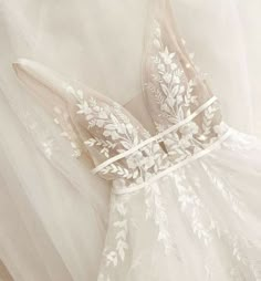 the back of a wedding dress with white flowers on it