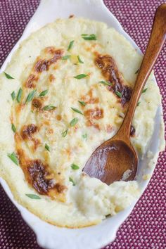 a white bowl filled with mashed potatoes and a wooden spoon on a purple cloth