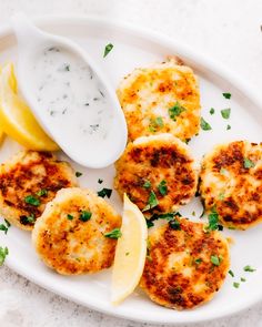 some crab cakes on a plate with lemon wedges