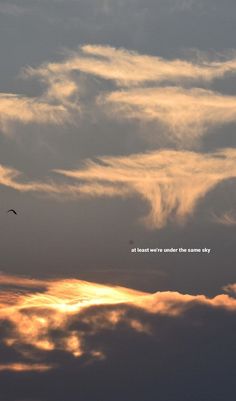 the sky is filled with clouds and birds flying in the distance as the sun sets