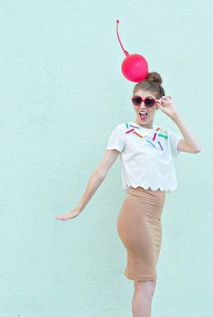 a woman in a skirt and t - shirt with a balloon on top of her head