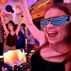 a group of people wearing 3d glasses are dancing in front of laptops and other electronic devices