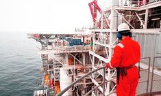 a man in an orange jumpsuit is standing on the deck of a ship looking out at the ocean