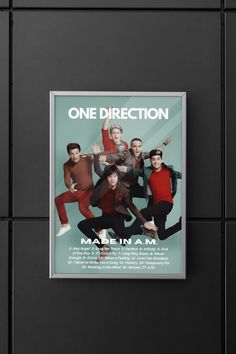 one direction poster hanging on the wall next to a black tile background with an advertise