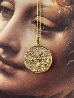 a close up of a gold necklace with an image of the face of jesus on it